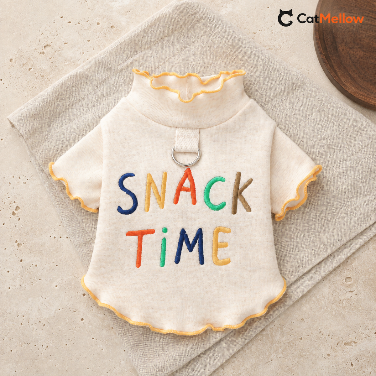 Cream CatMellow Snack Time embroidered cat T-shirt laid flat on neutral linen and stone