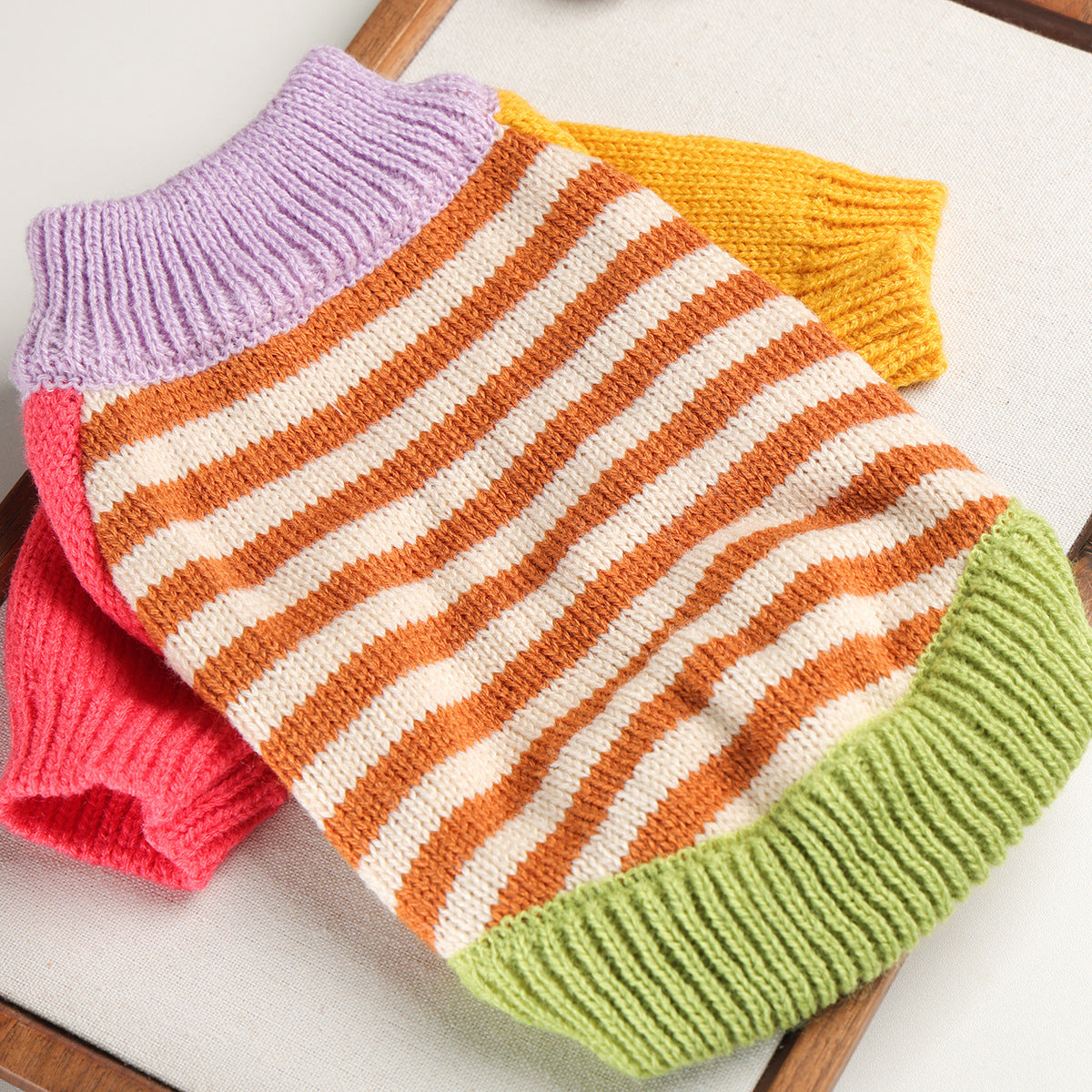 Color-block striped knit cat sweater laid flat to show the yarn texture.