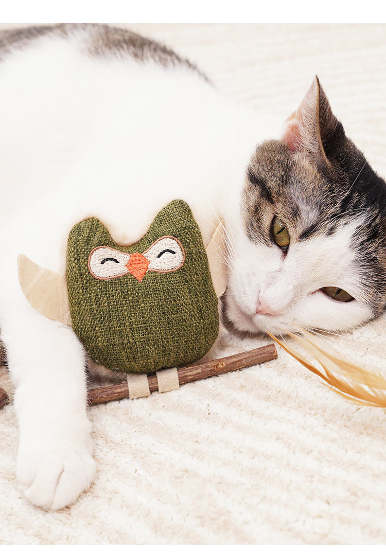 Cat resting beside the green owl toy