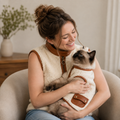 Original adult Western woman gently holding a Ragdoll cat in her arms, both wearing coordinated cream sherpa outfits with brown trim.