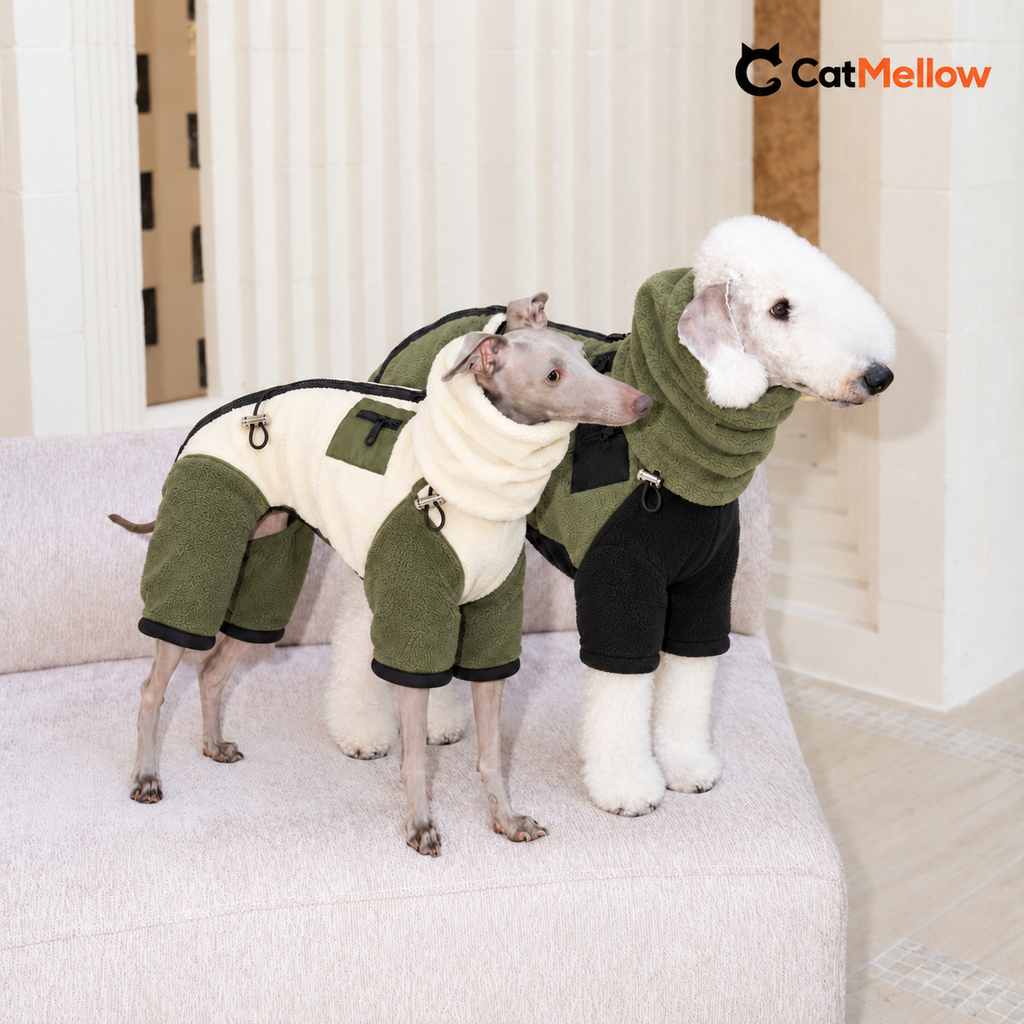 Two dogs on a cream sofa wearing cream-and-olive and olive-and-black fleece onesies with matching detachable snoods; CatMellow logo at the upper right.